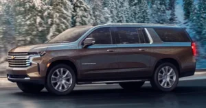 mrchauffeurcolorado | Stylish bronze 2025 Chevrolet Suburban cruising through a snowy landscape, showcasing its premium design and rugged capability