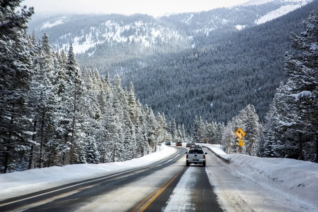 Winter highway through Colorado Rocky Mountains with cars driving to ski resorts — safe shuttle service and private transportation in snowy conditions.