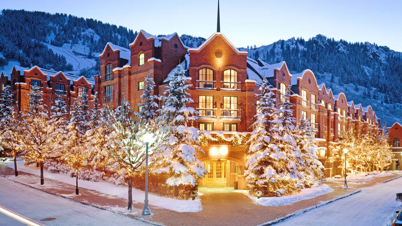 Luxury winter hotel in Aspen Snowmass Colorado with snowy mountains and holiday lights, perfect destination with reliable Aspen Snowmass shuttle service