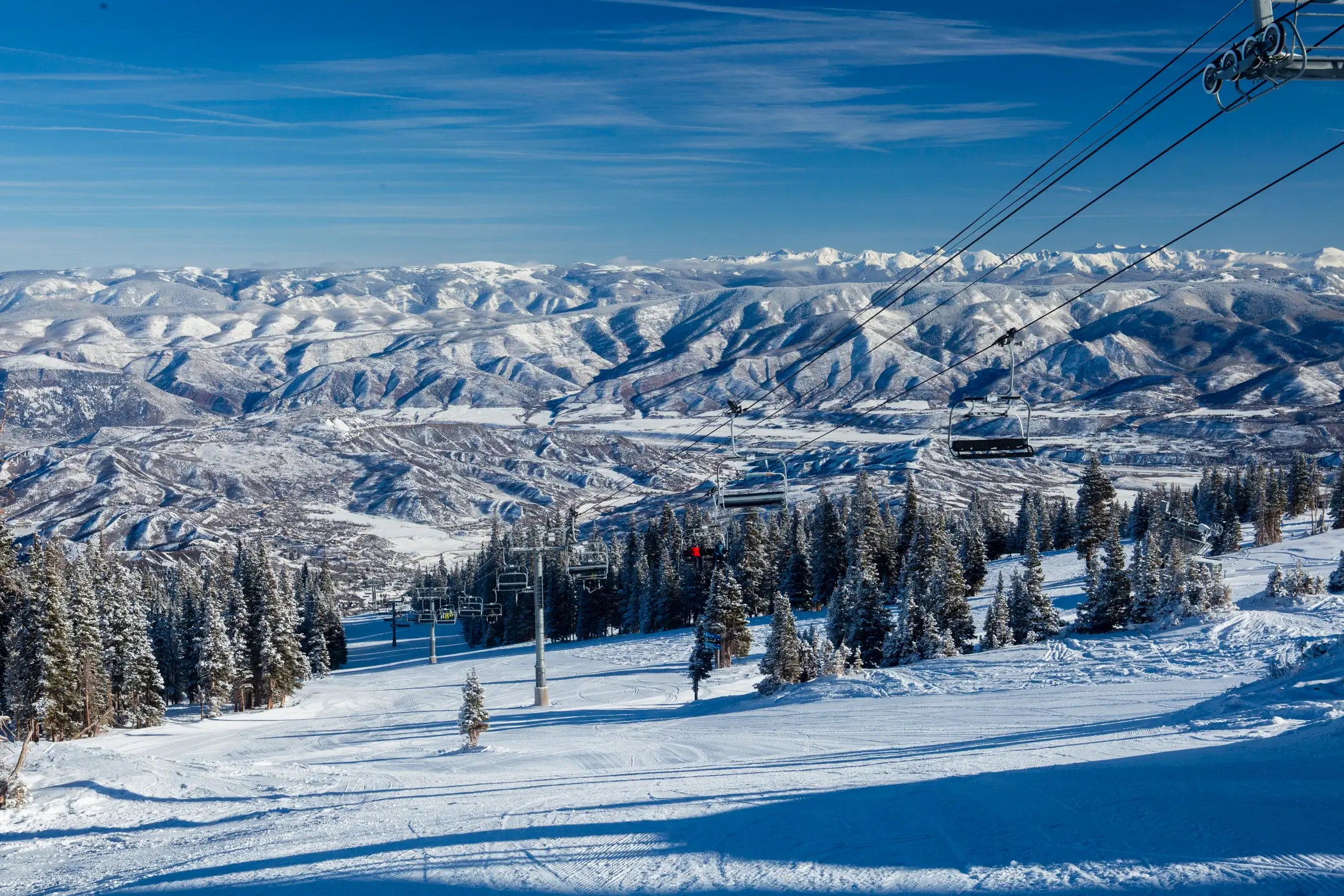 Scenic winter view of Aspen Snowmass ski resort with snow-covered mountains, ski lifts, and pine trees — ideal destination for reliable Aspen airport shuttle and transportation services