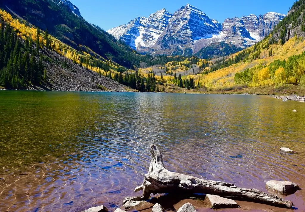 Stunning view of Maroon Bells near Aspen, Colorado in autumn with colorful foliage and calm lake — perfect destination served by Aspen airport shuttle and private transportation services