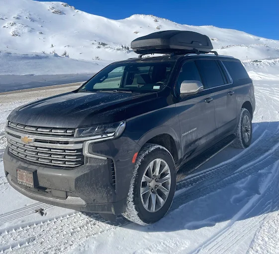 Private SUV shuttle service in Aspen Snowmass Colorado with luxury Chevrolet Suburban on snowy mountain road