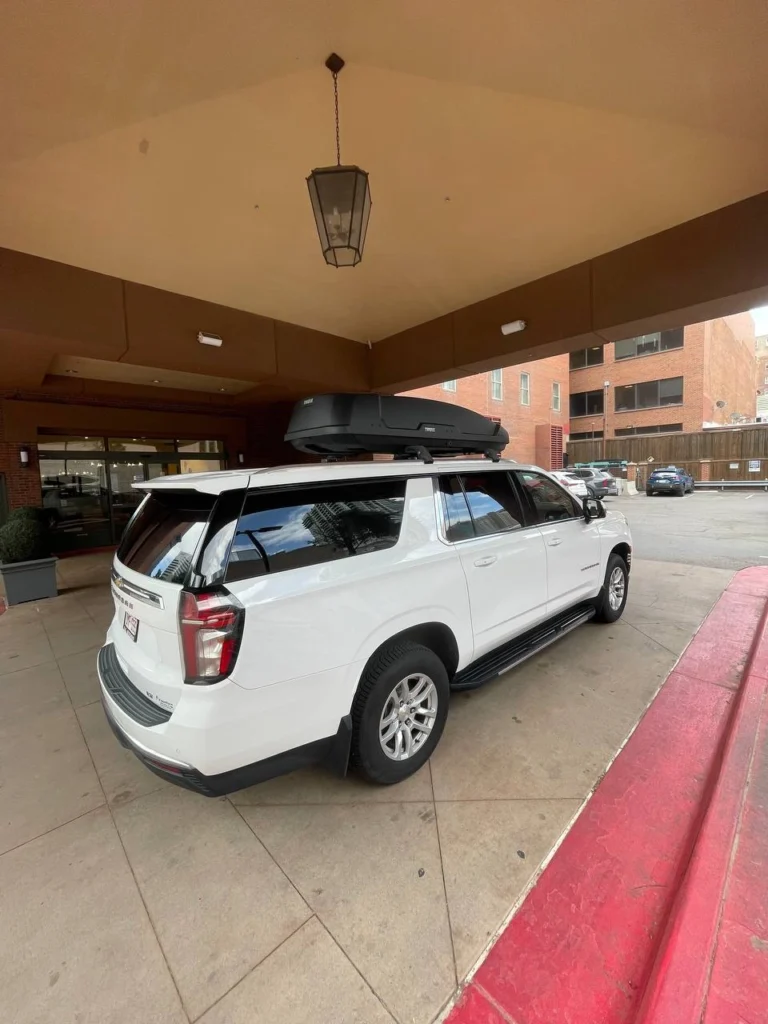 White luxury SUV with roof cargo box at hotel pickup. Private shuttle to Red Rocks Amphitheatre by Mr. Chauffeur Colorado.