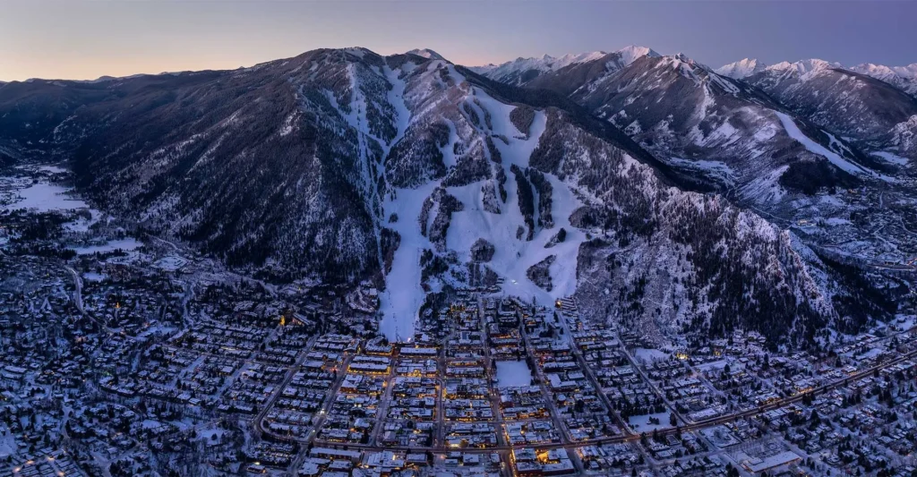Aspen Colorado winter aerial view of ski slopes and mountain town at dusk private car service from Eagle Vail airport