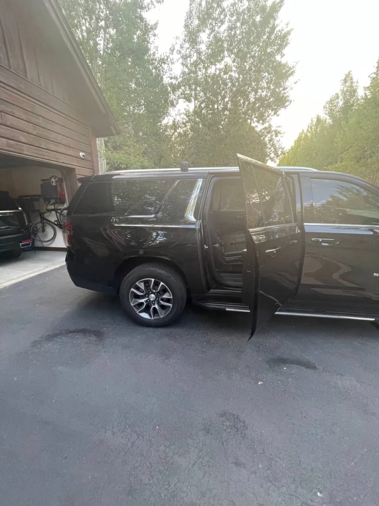 Black luxury SUV shuttle parked with rear passenger door open, ready for private chauffeur service