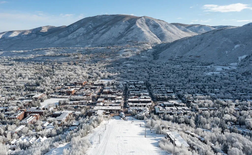 Aerial winter view of Aspen town with snow-covered buildings, trees, and surrounding mountains
