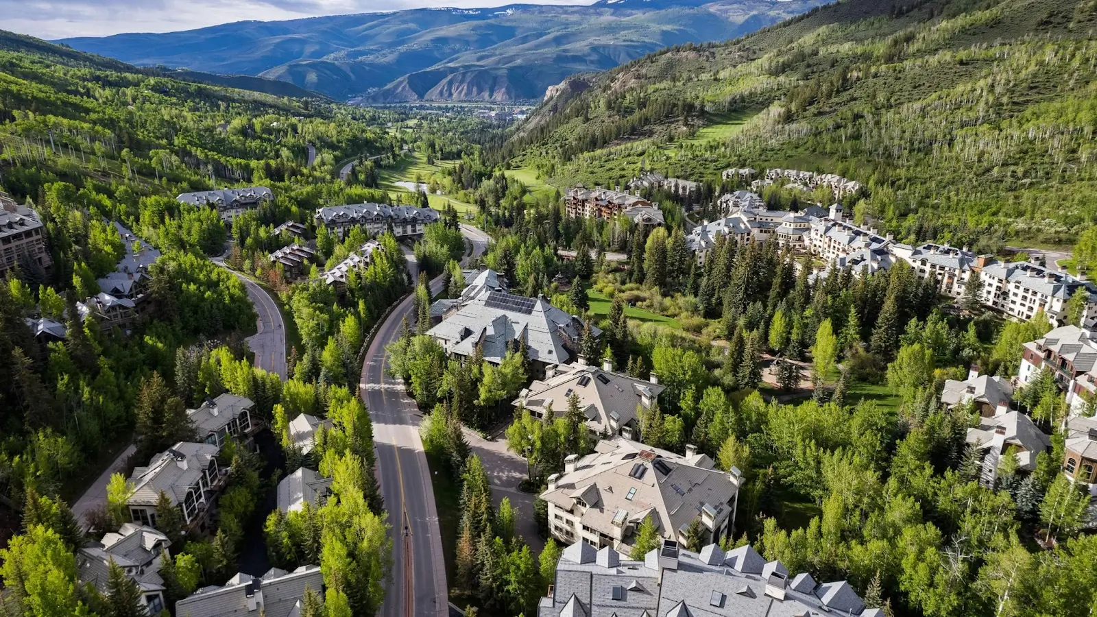 Aerial view of luxury mountain resort community in Beaver Creek, Colorado, surrounded by lush green forests and scenic roads.