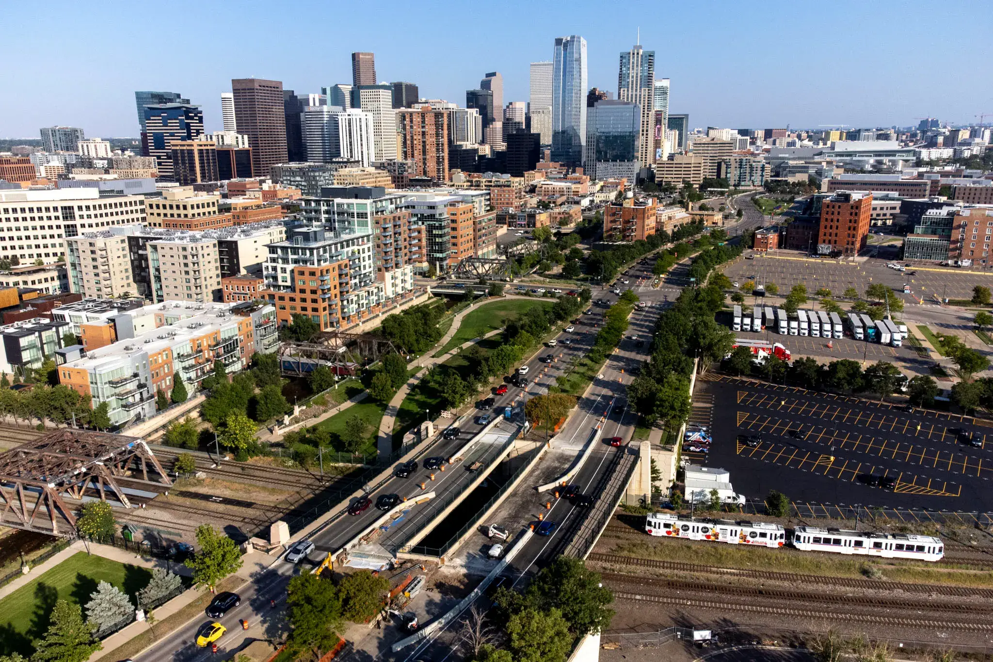 Aerial view of downtown Denver, Colorado, with modern skyscrapers, busy streets, and a light rail train passing through the city