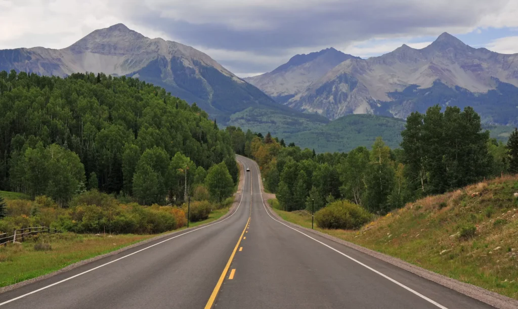 Scenic Colorado highway winding through lush green forests and mountains, Beaver Creek shuttle