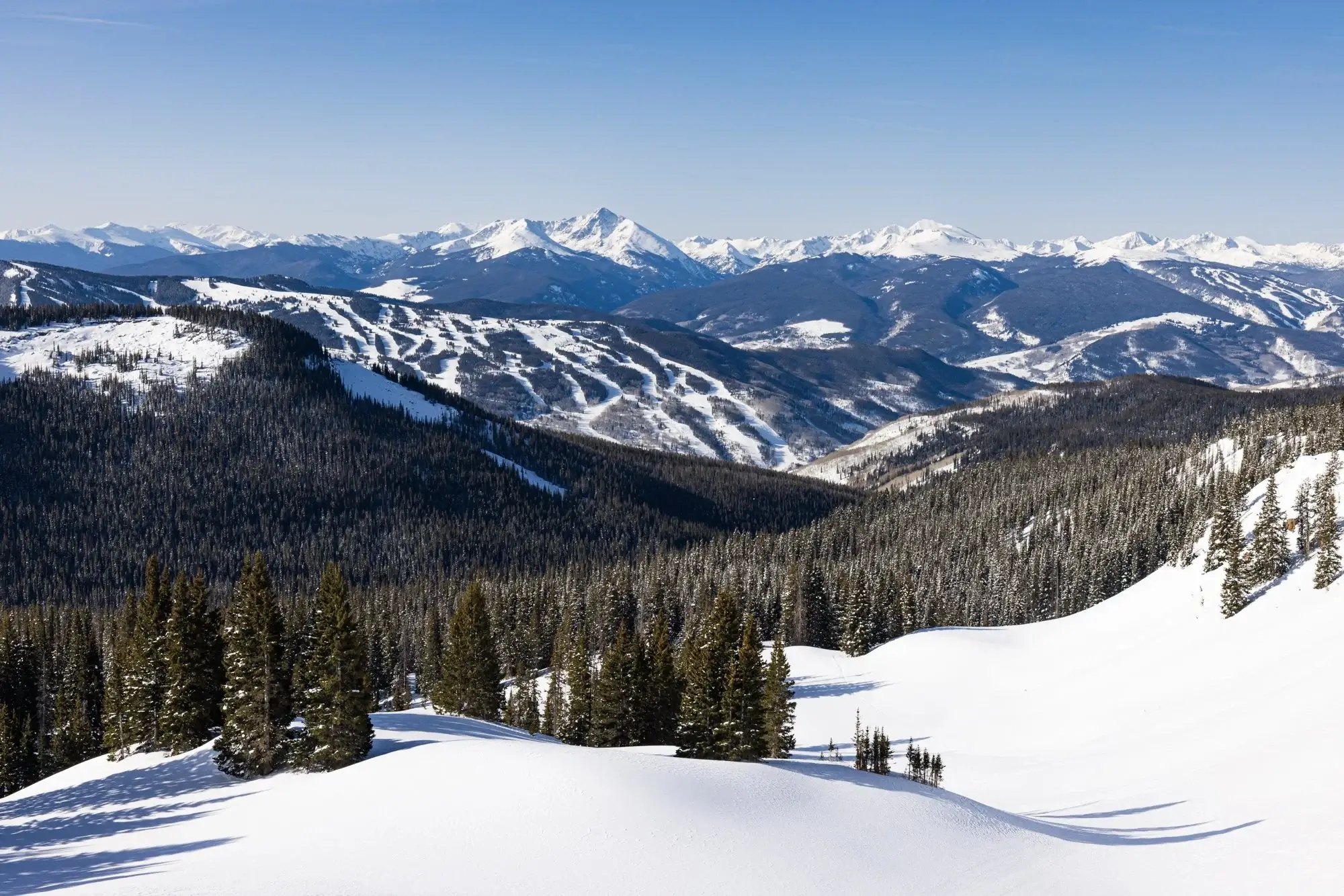 Snow-covered Vail Colorado Rocky Mountains with groomed ski runs and pine forests, perfect for shuttle service, airport transfers, ski resort shuttles, and mountain transportation