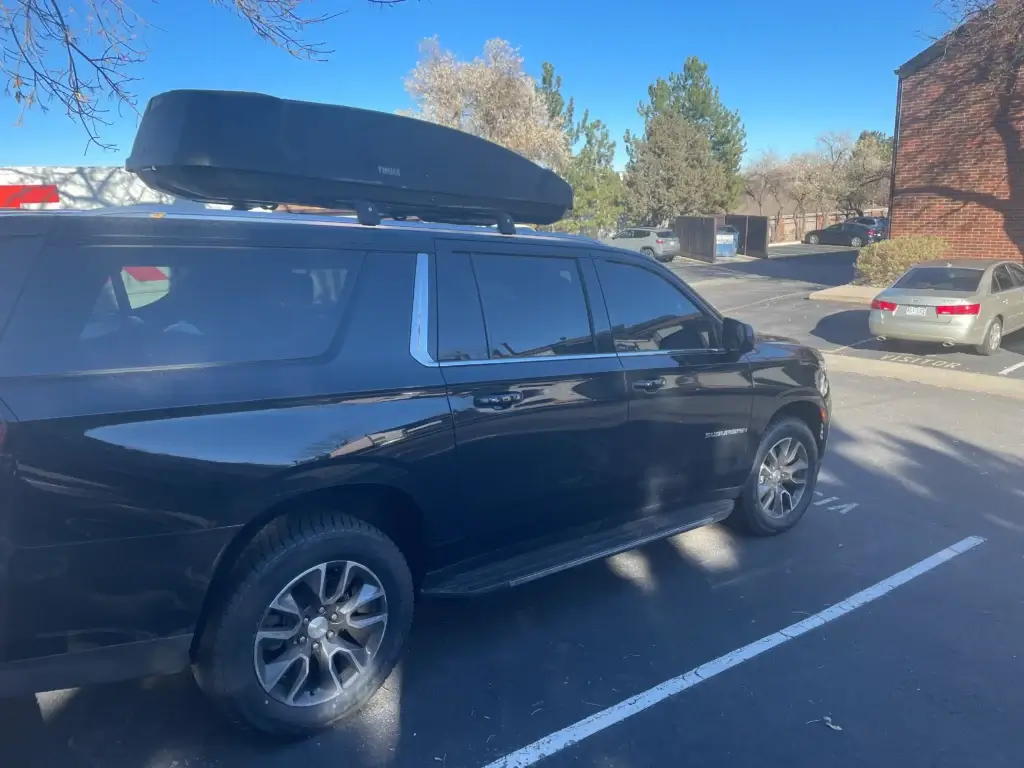 Black Chevy Suburban private shuttle with roof cargo box. Luxury airport transfer by Mr. Chauffeur Colorado.
