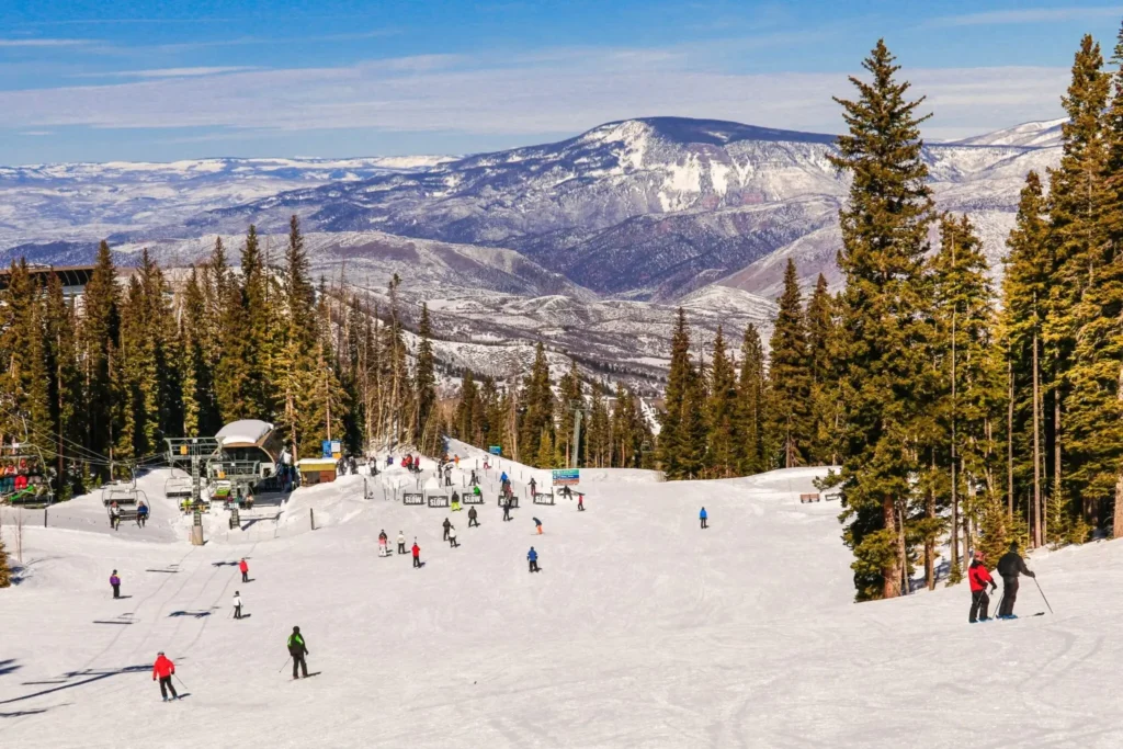 Mr. Chauffeur Colorado shuttle service: skiers enjoying a sunny Colorado ski slope featuring a chairlift and pine trees. Book reliable DIA airport transfer to top resorts like Vail, Aspen, and Breckenridge.