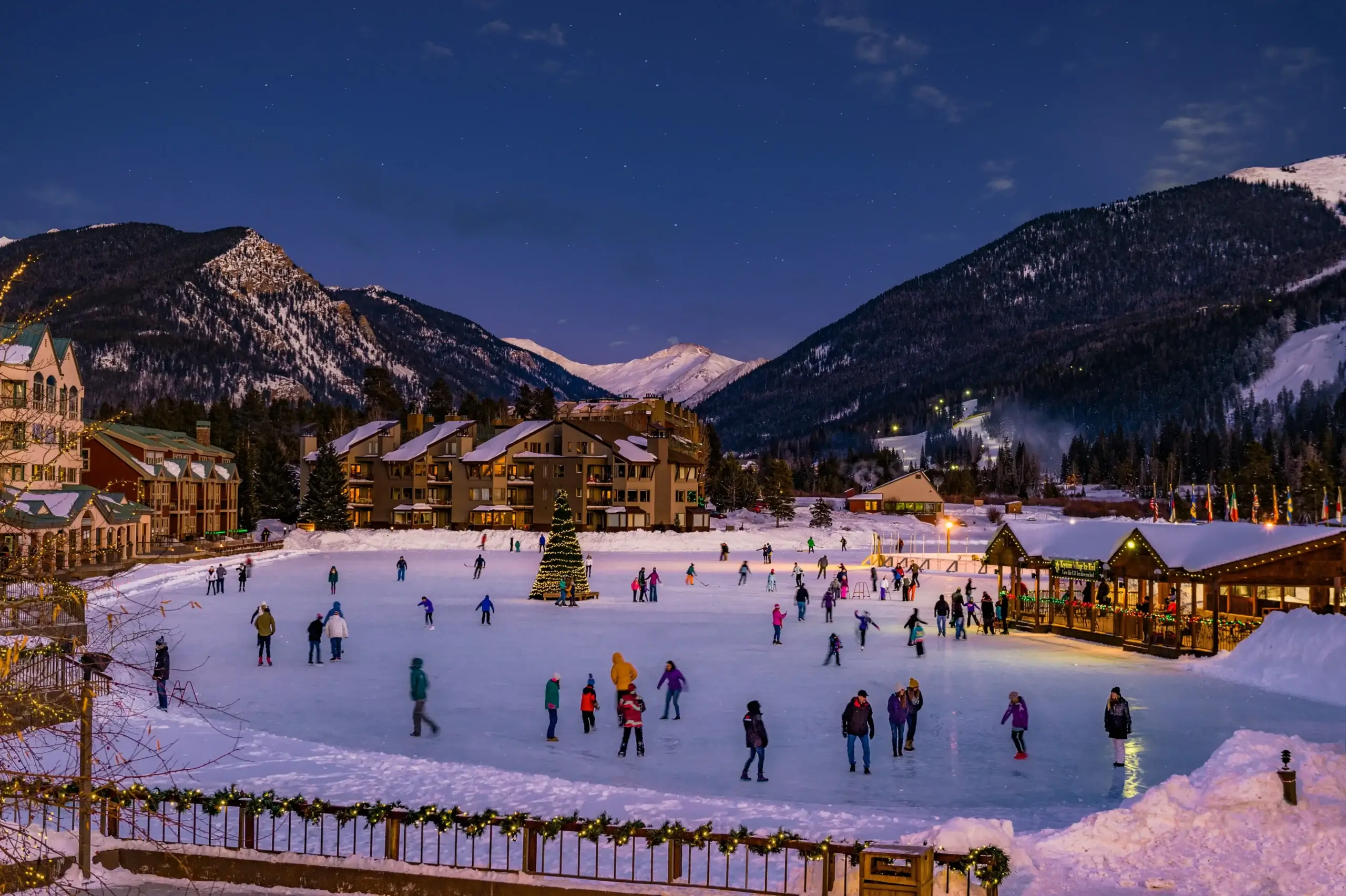 Keystone Village ice skating rink at night with holiday lights. Private shuttle from Denver to Keystone Resort by Mr. Chauffeur Colorado.