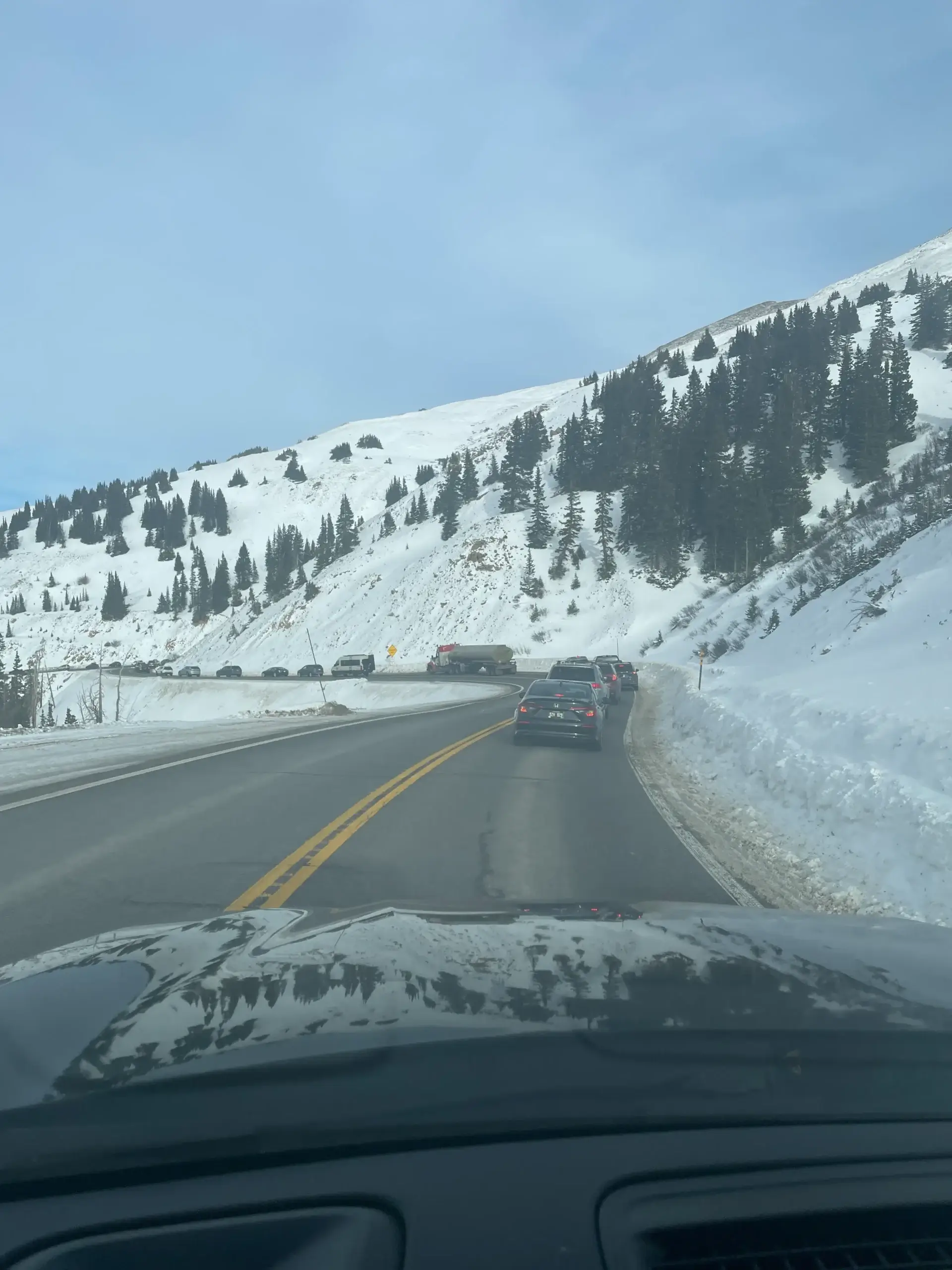 Winter traffic on a snowy, winding section of Interstate 70 in Colorado. Driving I-70 winter safety and traction law guide by Mr. Chauffeur Colorado.