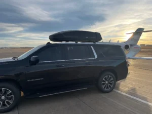 Luxury SUV from our fleet alongside a private jet. Private car service Mr. Chauffeur Colorado.
