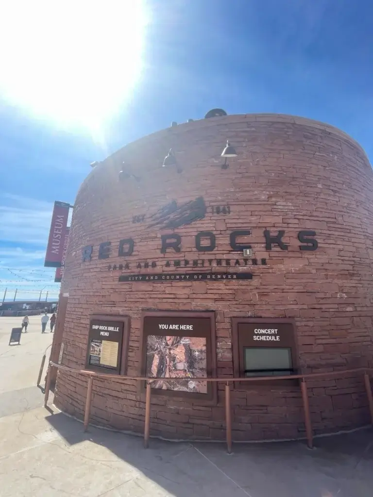 Red Rocks Amphitheatre entrance, iconic stone building with 'RED ROCKS' sign, Colorado.